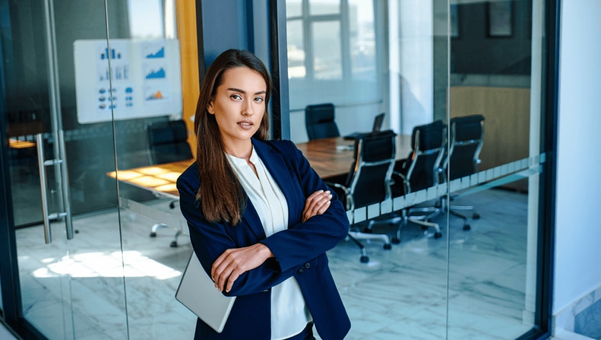 Femme souriante, bras croisés sur fond bleu, pour illustrer une formation en gestion d’entreprise proposée par CréActifs.