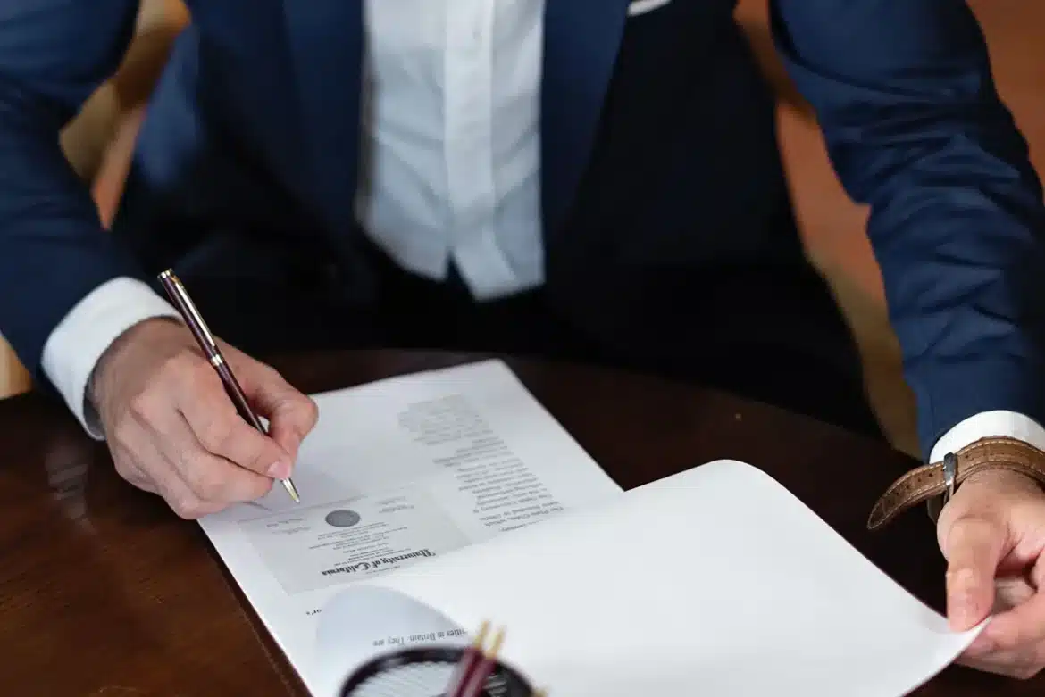 Mains tenant des documents administratifs français et une carte de séjour sur un bureau