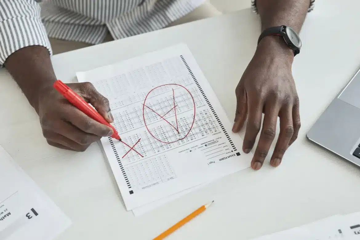 Feuilles d'examen et grille QCM sur un bureau d'étudiant avec un crayon