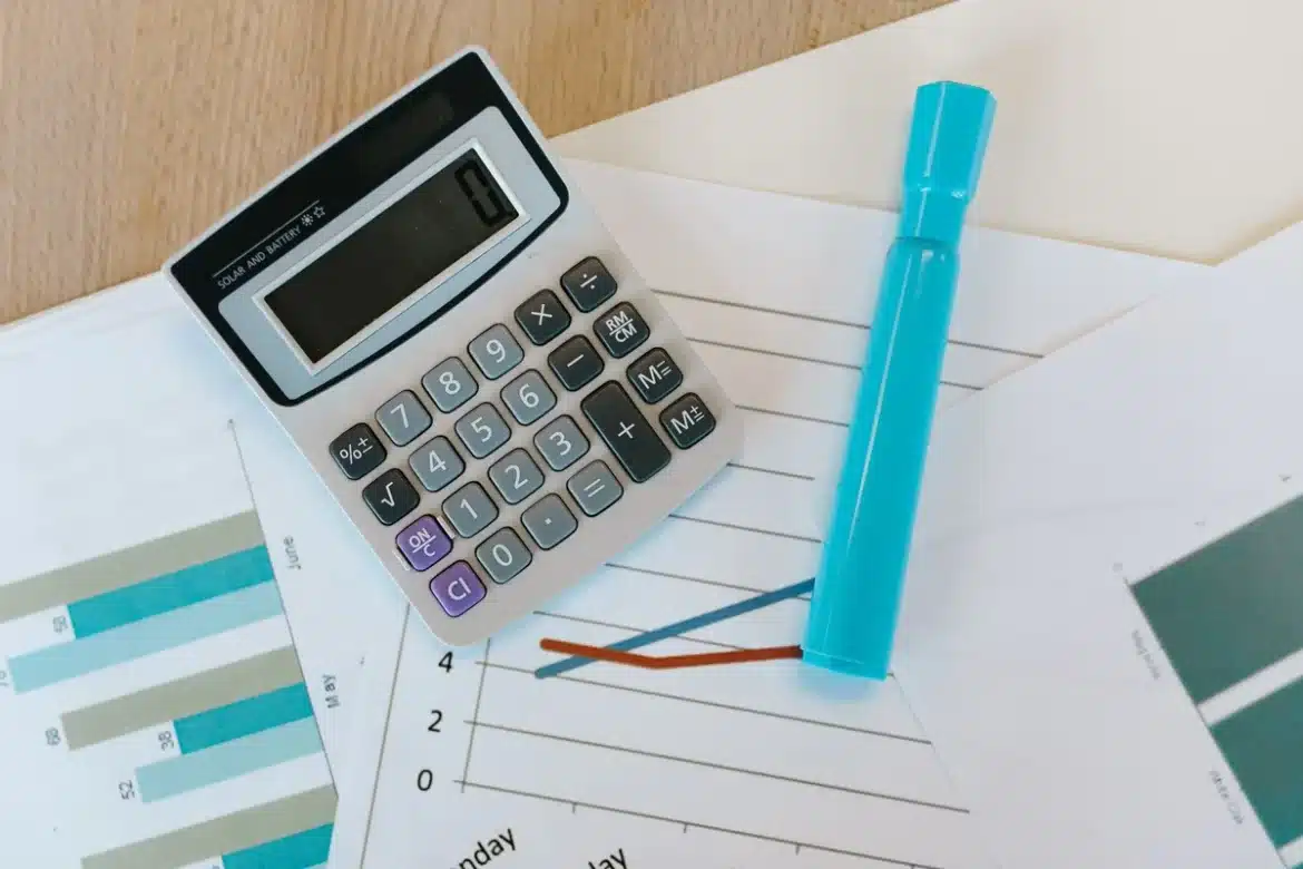 Documents d'investissement et graphiques financiers sur un bureau avec une tablette affichant des courbes d'indices