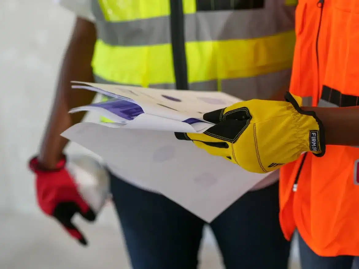 Documents de contrat de construction et plans étendus sur une table de travail avec stylo et presse-papiers