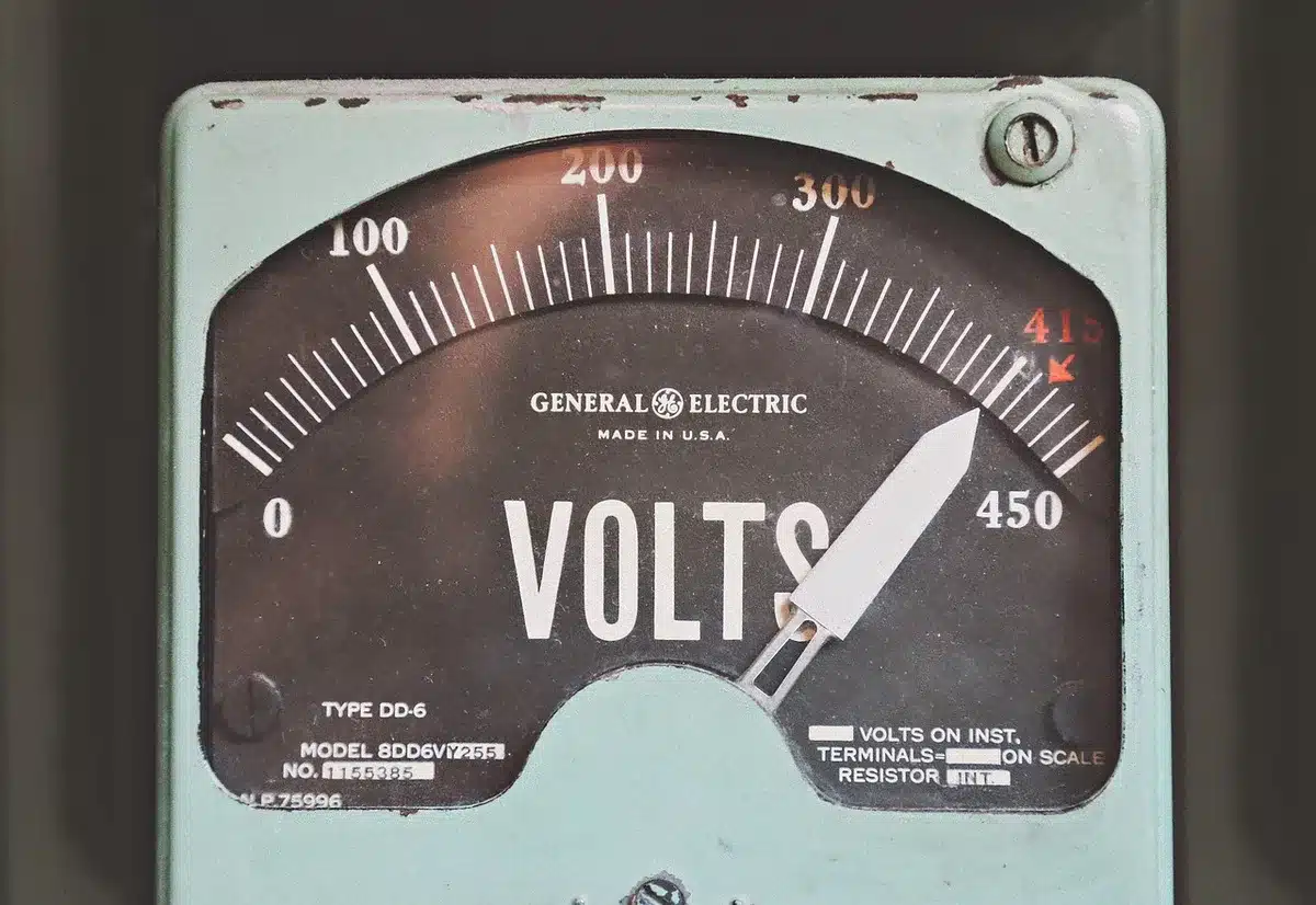 Main lisant la consommation sur un compteur électrique pour estimer le coût