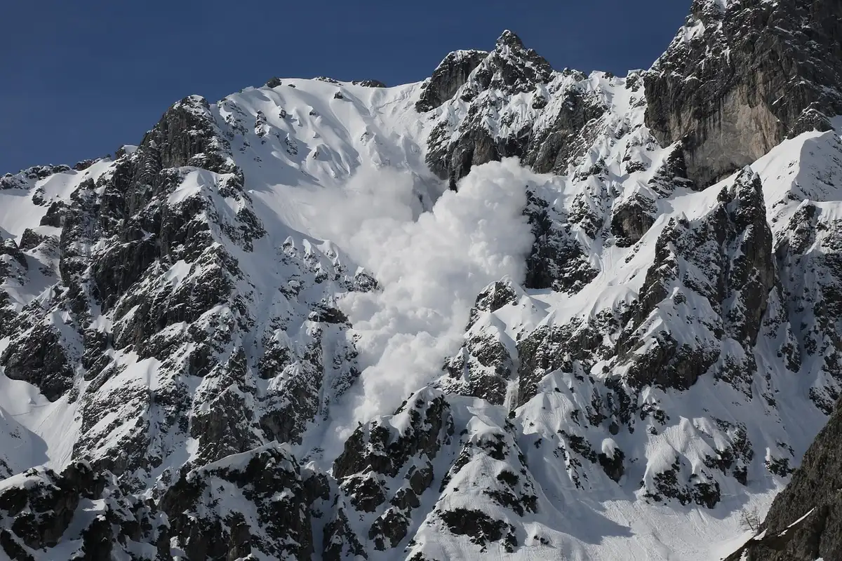 Coulée de neige dévalant une pente de montagne, démontrant la puissance d'une avalanche de plaque