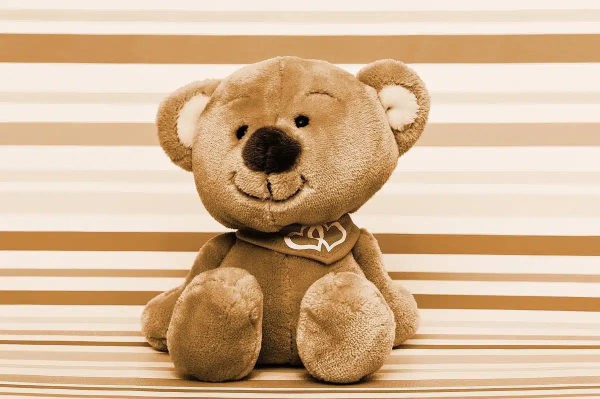 Peluche posée sur une table de classe avec enfants approchant la peluche