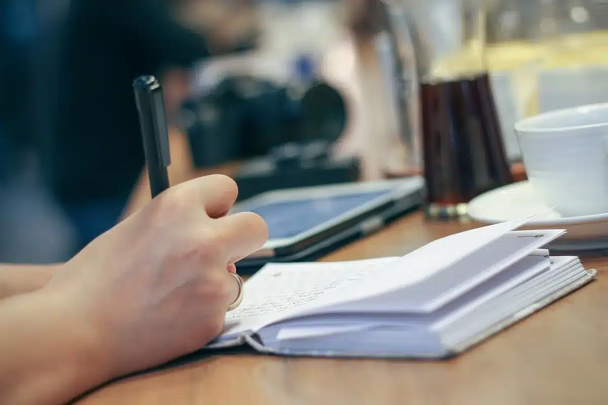 Cahier partagé et peluche sur une table où un enfant raconte le week-end de la mascotte