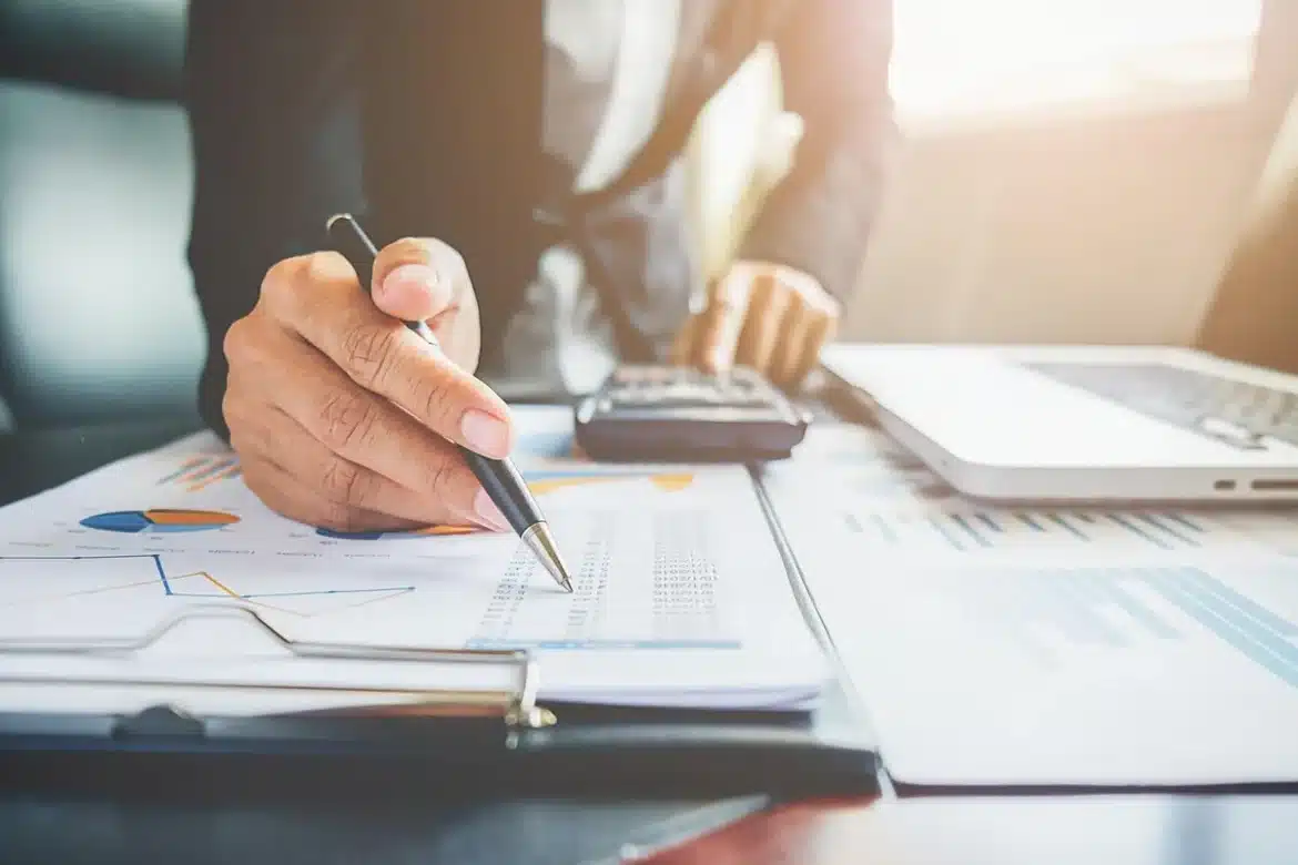 Bureau avec documents financiers, calculatrice et relevés d'épargne à côté d'une tirelire