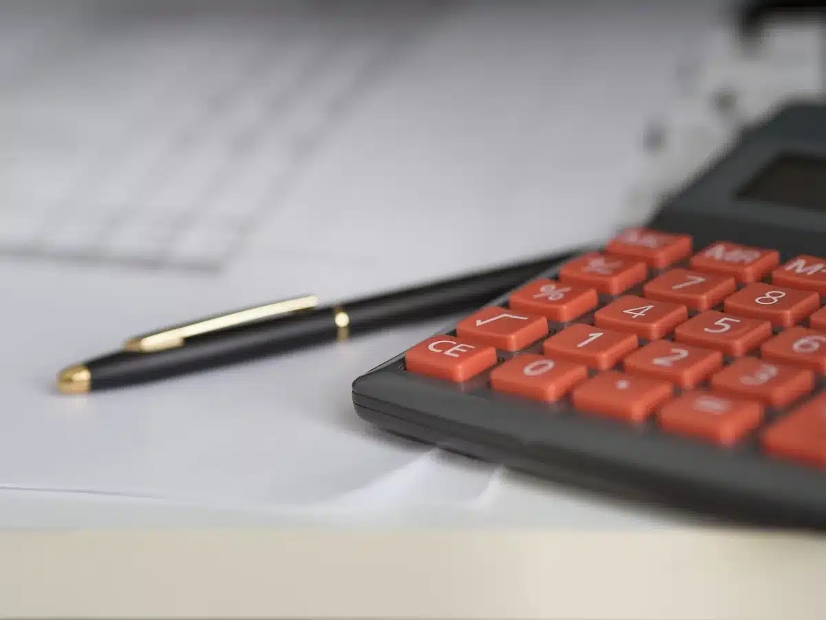Jeune étudiant calculant des mensualités avec une calculatrice et un échéancier