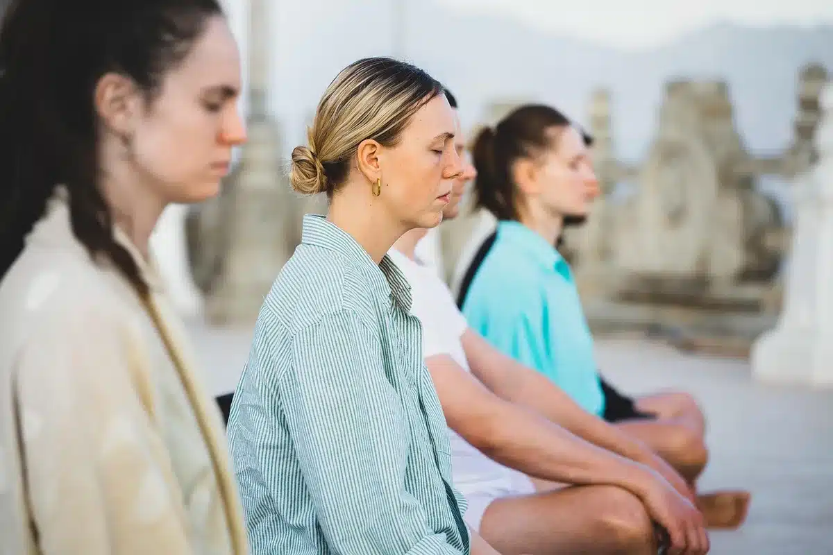Personnes pratiquant la relaxation et la respiration consciente dans un environnement calme et naturel.