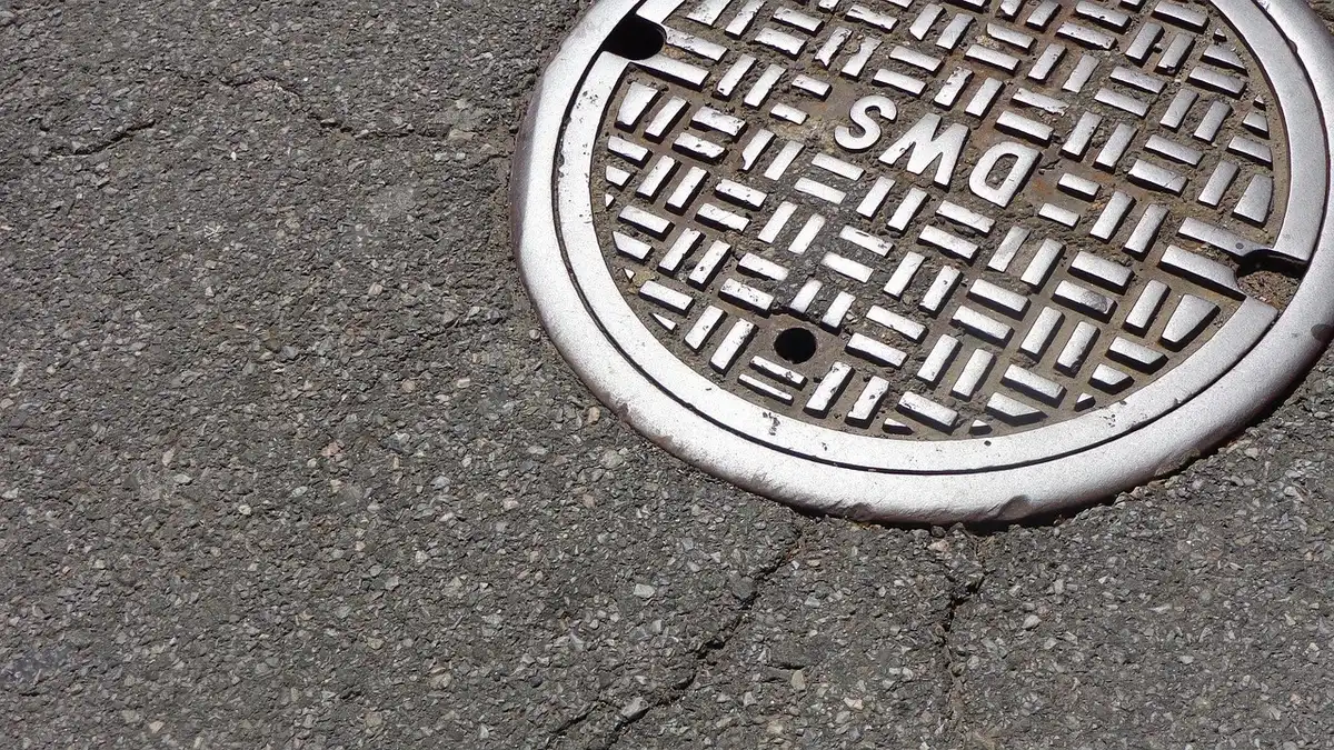 Plaque d'égout ouverte dans une rue urbaine montrant l'entrée souterraine