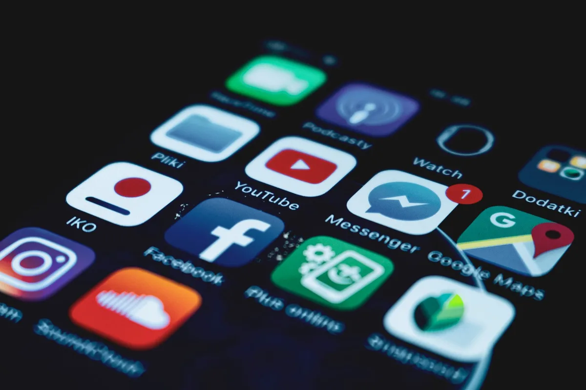 Main tenant un smartphone montrant des notifications de réseaux sociaux