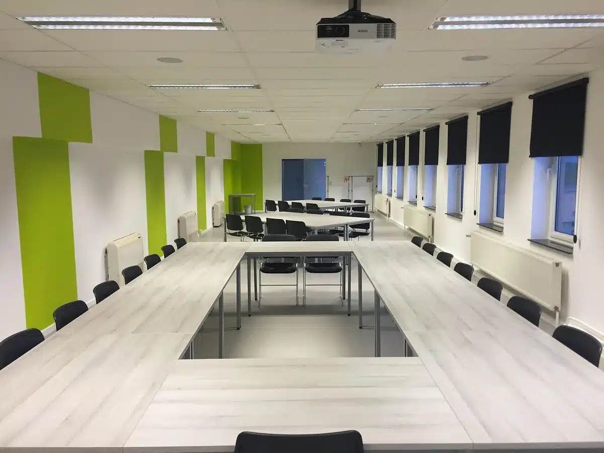 Salle du conseil municipal en journée avec rangées de chaises et une table du maire