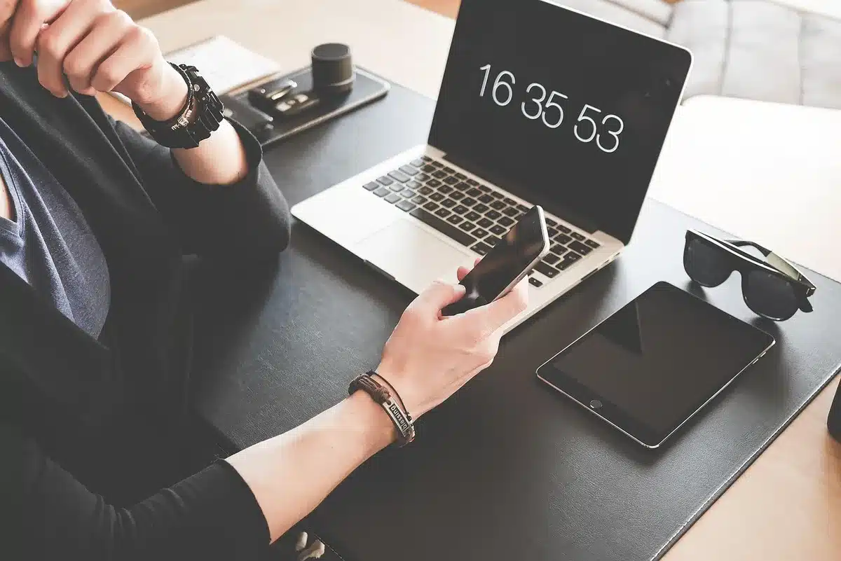 Main prenant une capture d'écran d'un appel sur un smartphone posé sur un bureau
