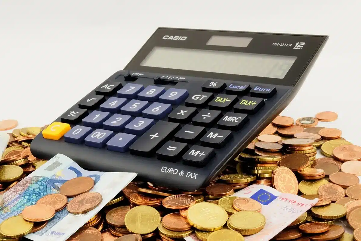 Personne calculant ses options d'épargne avec une calculatrice à la lumière du jour
