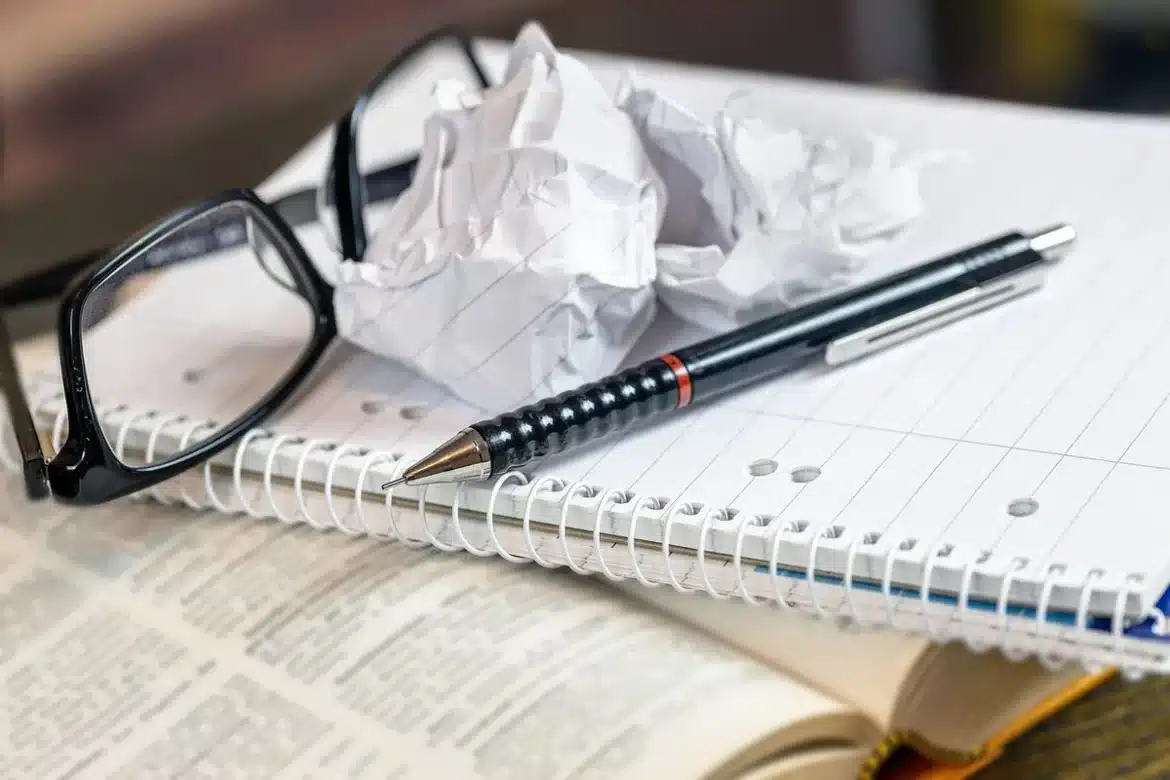 Bureau en plein jour avec carnet, calculatrice et relevé bancaire flou en arrière-plan